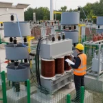 Engineer reviewing reactive power meaning beside an outdoor HV capacitor frame